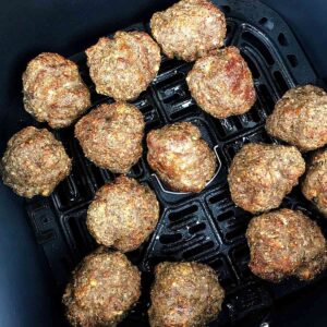 cooked meatballs in an air fryer basket
