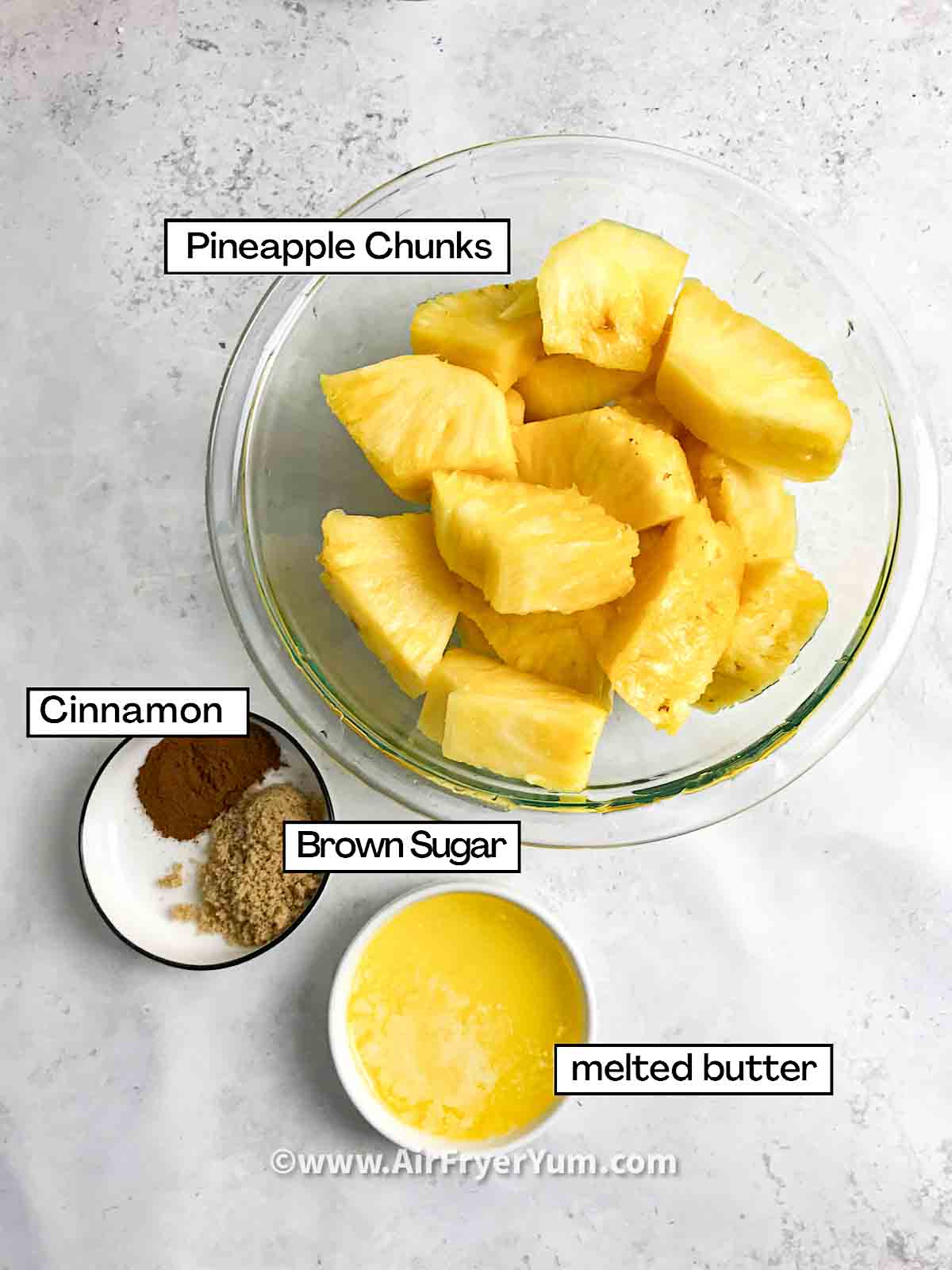 Image showing Ingredients which include a bowl
of pineapple chunks, a small bowl of melted butter and a small bowl of cinnamon and brown sugar